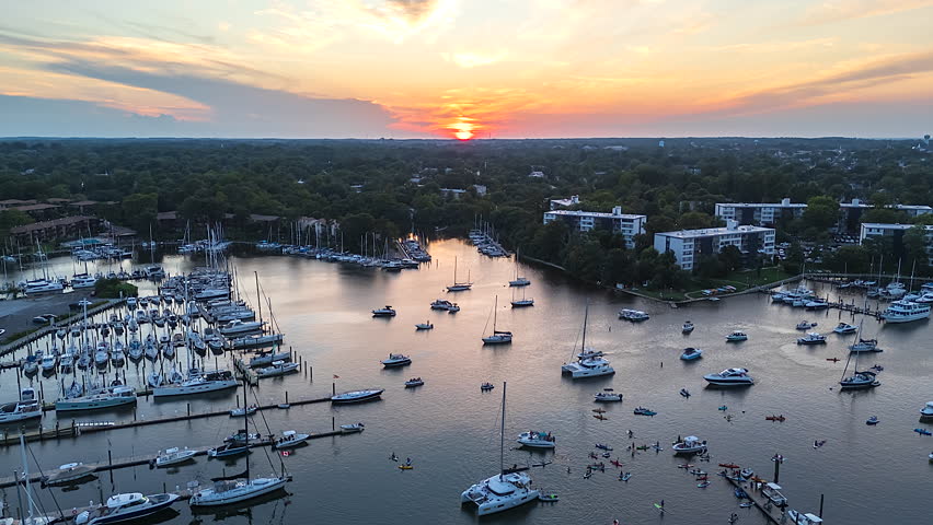 A Tranquil Marina in Back Creek Annapolis, MD Filled With Boats Reflects the Warm Glow of the Sunset Over a Tree-lined Waterfront Town - Timelapse