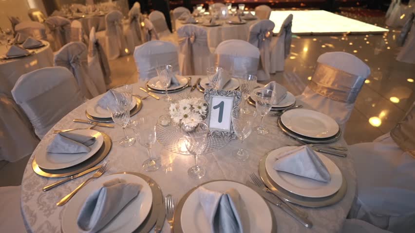 Wide orbit of elegant banquet table setup with plates glassware and refined decor, disco lights flash overhead