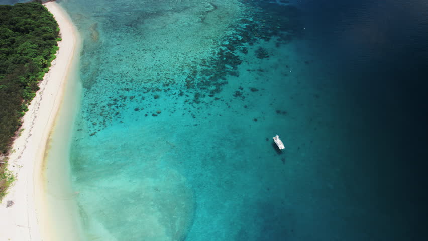 Aerial drone footage revealing the turquoise waters, coral reef, and white sandbanks surrounding Frankland Islands in the Great Barrier Reef, Queensland, Australia.