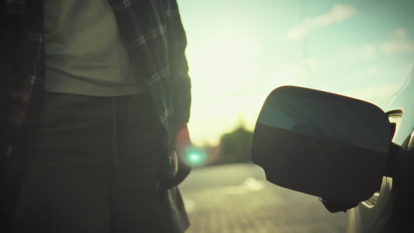 Young woman confidently inserts fuel nozzle into her car, efficiently refilling the tank on sunny street, showcasing her independence while driving, embodying capable, young driver in open public area