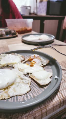 a man eats scrambled eggs with a fork. Breakfast on a warm sunny morning, a sunbeam shines directly on a plate of food. A man eats breakfast with scrambled eggs, cutting them into pieces with a table