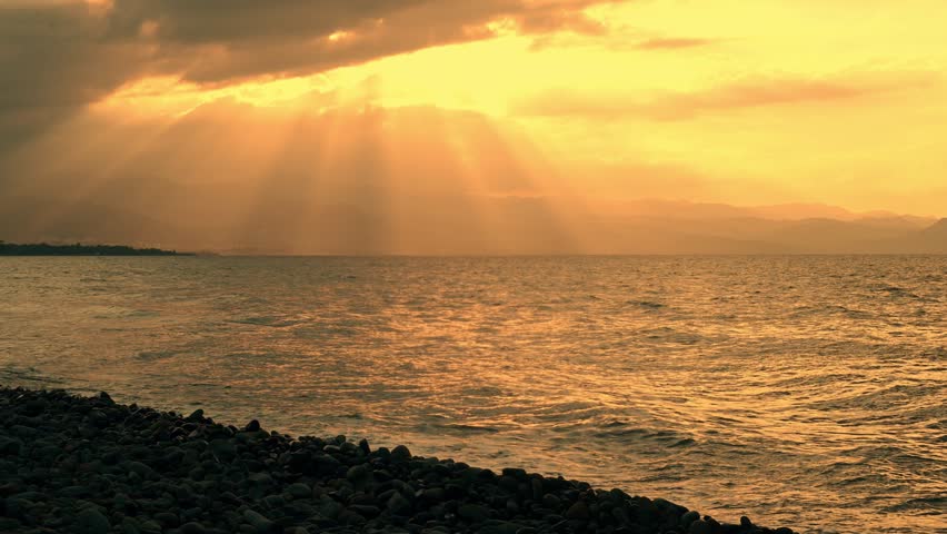 Beautiful sunset over a sandy beach in Cyprus. Gentle waves of the Mediterranean Sea glow in the golden hour light. Serene and iconic travel backdrop.