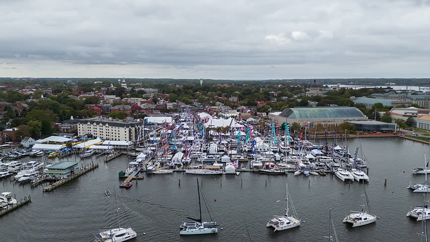 Annapolis Boat Show. A Bustling Waterfront Festival Fills the Marina, With Rows of Boats, Colorful Flags, and Tents Set Against a Townscape Under a Cloudy Sky - Hyperlapse