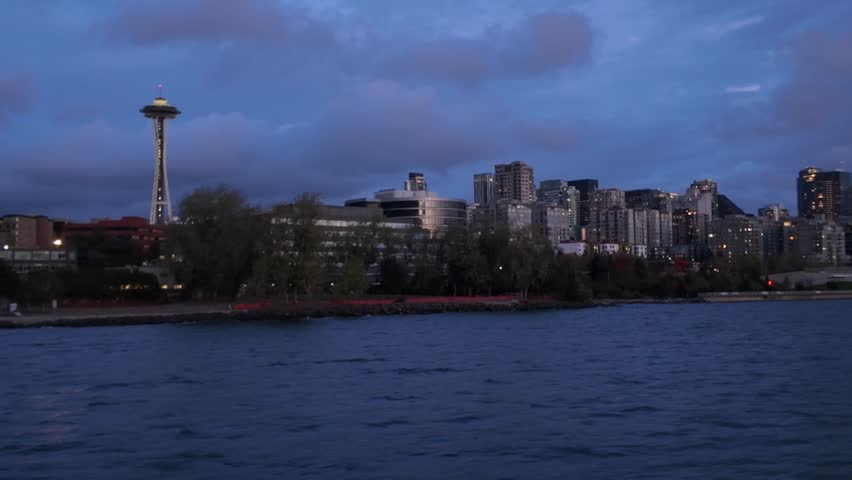 Gimbal wide panning shot of Seattle as seen from a moving boat on the Salish Sea during twilight in Washington. 4K at 30 FPS
