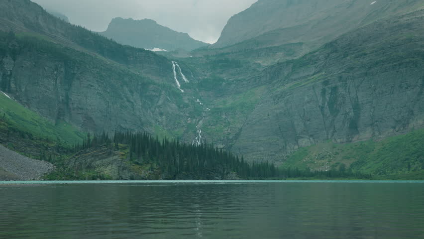 Serene mountain lake in Montana with a waterfall, peaceful and scenic