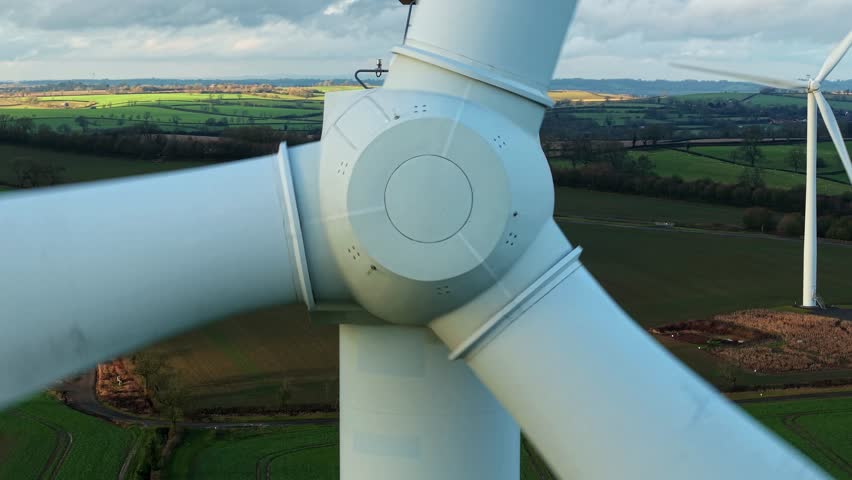 Aerial view of wind turbines standing tall against patchwork fields, creating a dynamic contrast of modern energy and rural landscape, Kelmarsh, United Kingdom.