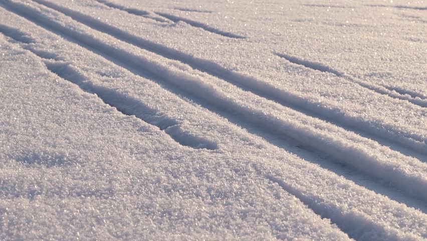Ski tracks in the snow. White snow-covered ground or surface of a frozen lake. Skier