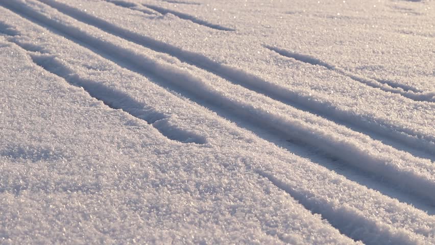 Ski tracks in the snow. White snow-covered ground or surface of a frozen lake. Skier