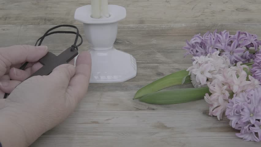 Female hand with Wooden cross necklace with spring hyacinths, Easter, faith, and spring themes, resurrection and new life, Religious still life and flowers