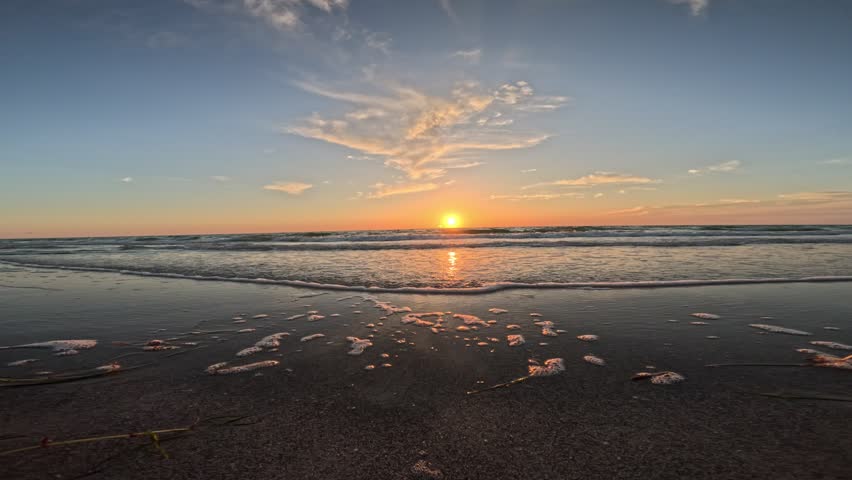 Waves lapping at camera from a low beach preservative making it feel like you are there at sunset on Belleair Beach, just outside of Tampa Bay. Waves lapping, sun setting beauty. 4k