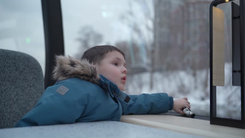 Child looking out the window of a moving river ship. Travel scene inside public transport.