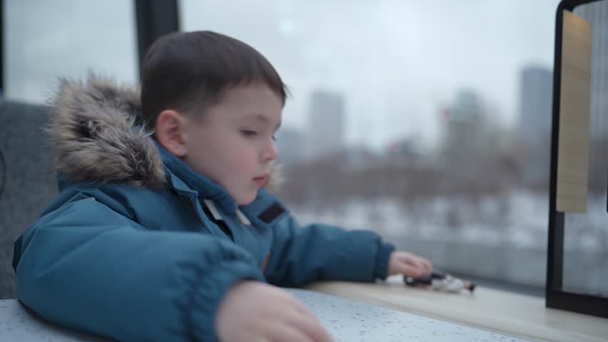 Child looking out the window of a moving river ship. Travel scene inside public transport.