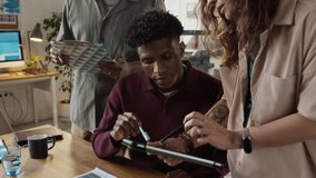Tilt-down shot of diverse colleagues using digital tablet while working on project in modern design bureau - Powered by Shutterstock - Get 15% off with code: PIKWIZARD15