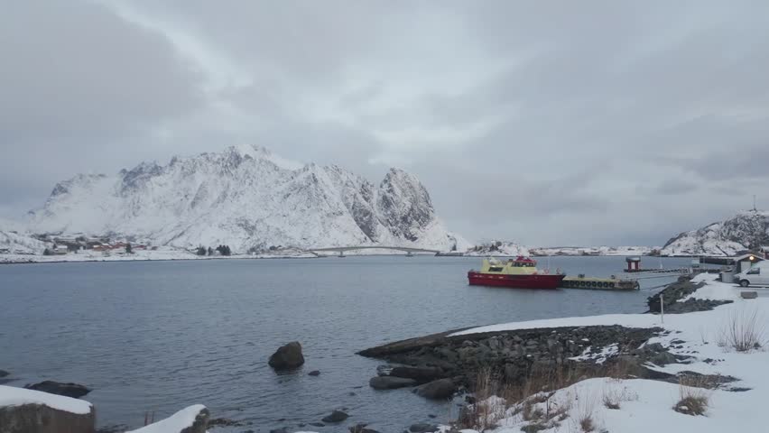 Panoramic view of the scenic Reine fishing village in Lofoten Islands, Norway, covered in snow during winter season.Beautiful arctic landscape with traditional red wooden houses (Rorbu) and snow-capped mountains in Lofoten, Norway.