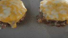 Slow motion of fast food kitchen restaurant conveyer belt cooking and grilling multiple cheese burgers cheeseburgers on griddle stove top fryer as juicy meat for quick meal is smoking and burning 4k - Powered by Shutterstock - Get 15% off with code: PIKWIZARD15