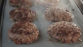 Slow motion of fast food kitchen restaurant conveyer belt cooking and grilling multiple cheese burgers cheeseburgers on griddle stove top fryer as juicy meat for quick meal is smoking and burning 4k - Powered by Shutterstock - Get 15% off with code: PIKWIZARD15