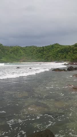 Dramatic Ocean Waves Crashing on Tropical Beach Shore Under Cloudy Sky