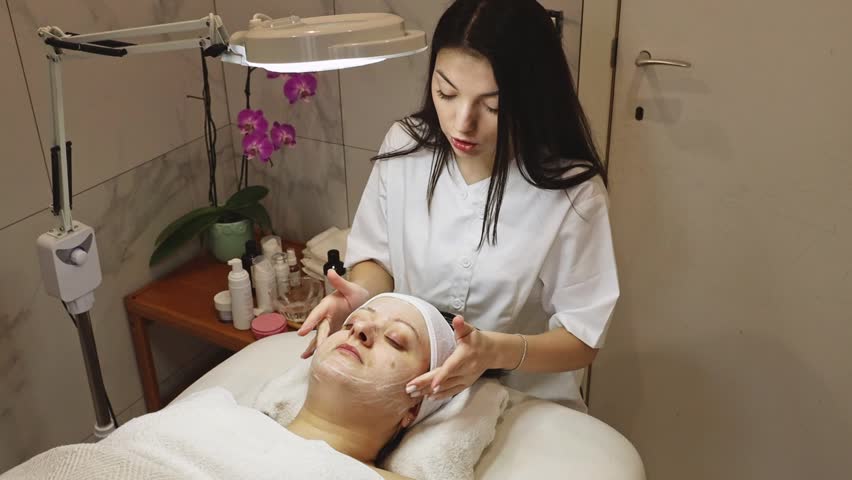 Young Caucasian cosmetologist foaming woman