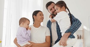 Family parents children smiling together at home. Parents hold a baby and a daughter, sharing warmth and love in a bright room. Happiness and unity indoors. Concept: family portrait at home. - Powered by Shutterstock - Get 15% off with code: PIKWIZARD15
