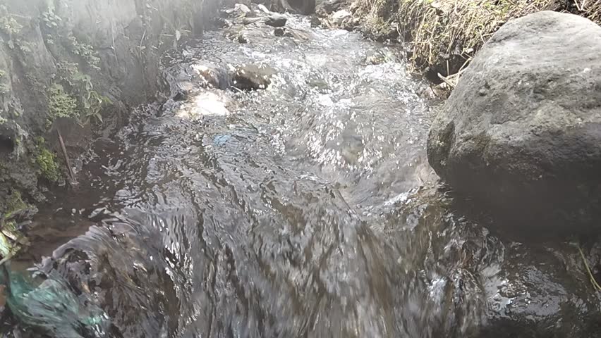 Top view of splashing white water in a fast-flowing mountain stream. High-speed water texture for nature backgrounds, environment, and energy themes
