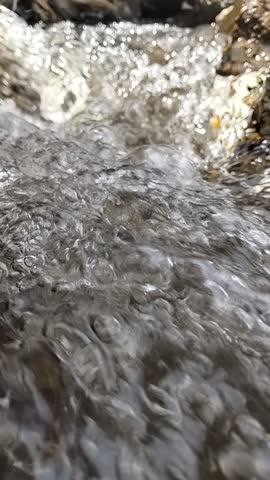 Top view of splashing white water in a fast-flowing mountain stream. High-speed water texture for nature backgrounds, environment, and energy themes