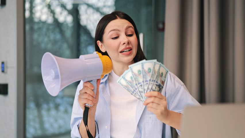 Confident woman holds megaphone and fan of dollar bills, smiling happily while making important announcement. Expresses joy and excitement for financial success or big promotion.