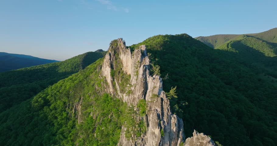 Aerial fast orbit left of Seneca Rocks emerging from the Appalachian forest landscape, shadows and light separated