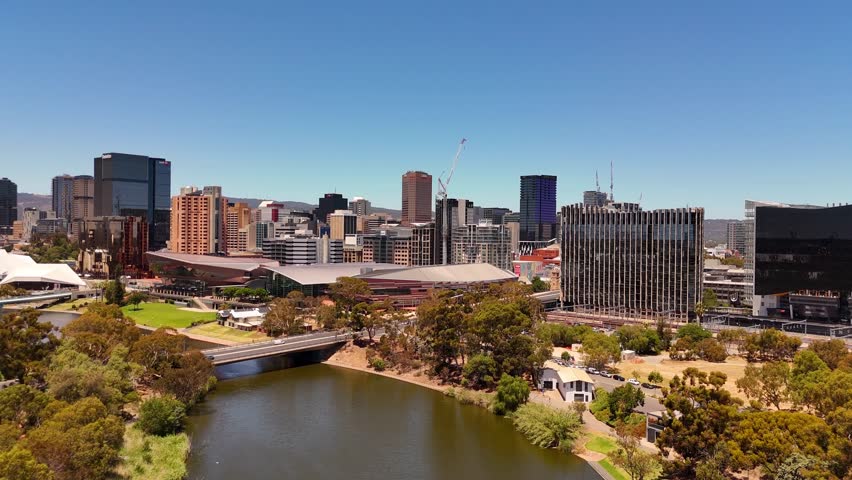 Aerial establishing dolly of Adelaide skyline with riverbank, city parks convention centre, and downtown buildings