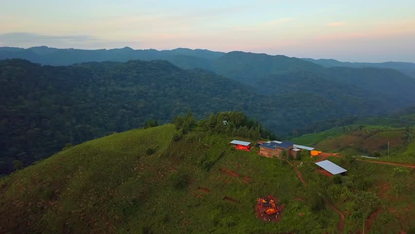 Aerial view showing changing landscape in Rubanda District, Uganda, with a tea plantation on steep hills overlooking the vast Bwindi Impenetrable Forest and a humble human settlement farming structure