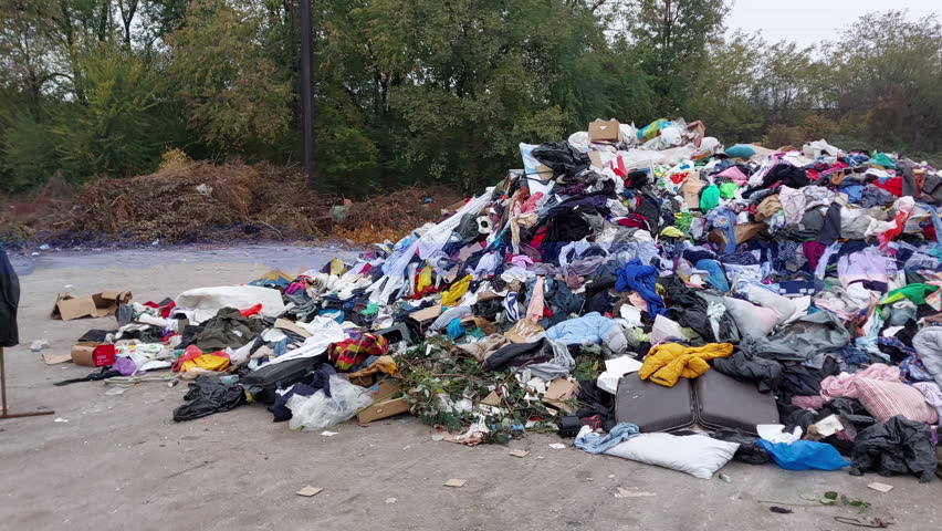 Large mountain of worn clothing and garbage. Concept of waste, pollution, and irresponsible consumption, 4k