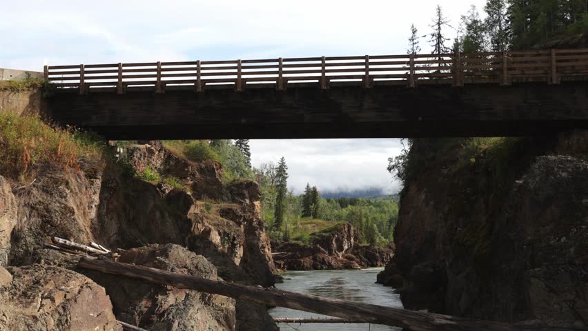 Downward panning shot over a narrow river with high rocky walls as migrating salmon move upstream during daylight in British Columbia, Canada.