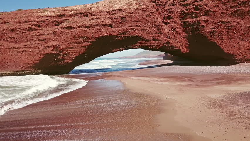 Flying through the arch on Legzira beach with arched rocks on the Atlantic coast in Morocco, 4k