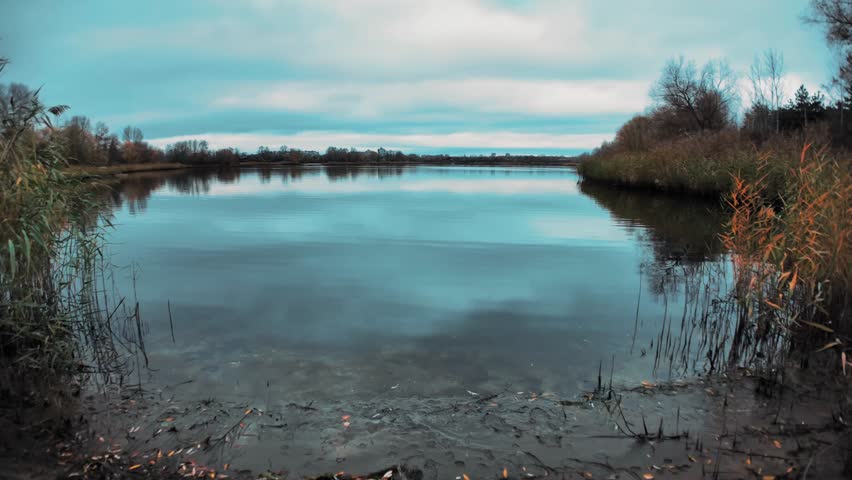 Beautiful autumn landscape with a lake and blue water. Landscape in cinematic colors. Sunset on the lake. 4K 60fps.
