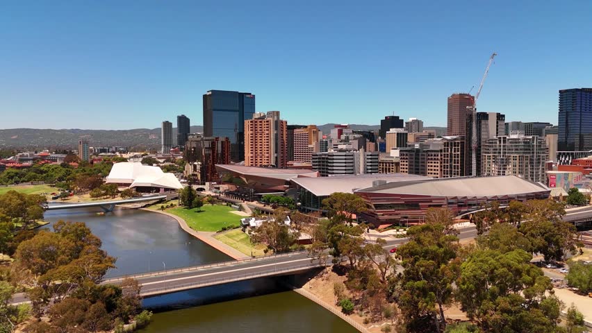Aerial establishing orbit of Adelaide convention city center with river, bridges, and urban park areas