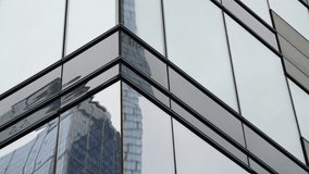 Angular glass facade of a modern office building capturing distorted reflections of a neighboring skyscraper, emphasizing geometric lines, mirrored surfaces, and urban symmetry - Powered by Shutterstock - Get 15% off with code: PIKWIZARD15