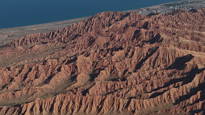 Dramatic aerial orbit around jagged red clay formations in Kyrgyzstan