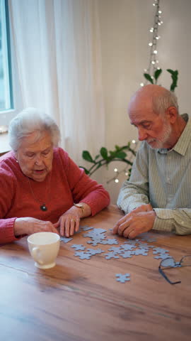 Senior couple solving jigsaw puzzle together at home.