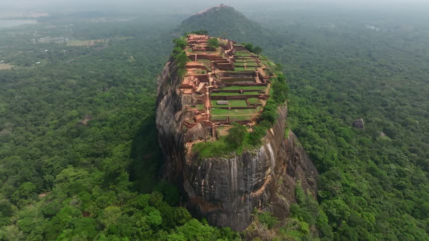 Sri Lanka aerial view of Sigiriya rock citadel with green terraces and brick structures, emphasizing the dramatic cliff-top setting.