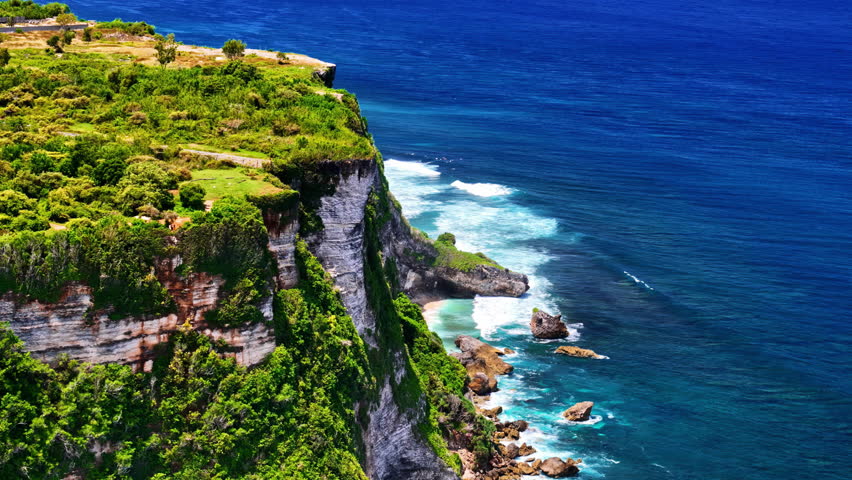 High-angle drone shot of the dramatic limestone coastline and turquoise sea at Nyang Nyang Beach featuring powerful waves and rugged cliffs in South Kuta