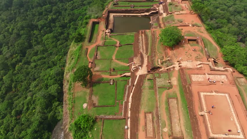Sri Lanka drone flyover of Sigiriya Rock Fortress with summit ruins and surrounding forest canopy.
