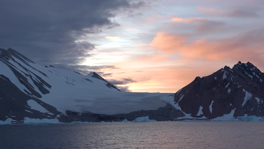 Landscape of Greenland with mountains, icebergs, and calm water in the evening light near the fjord