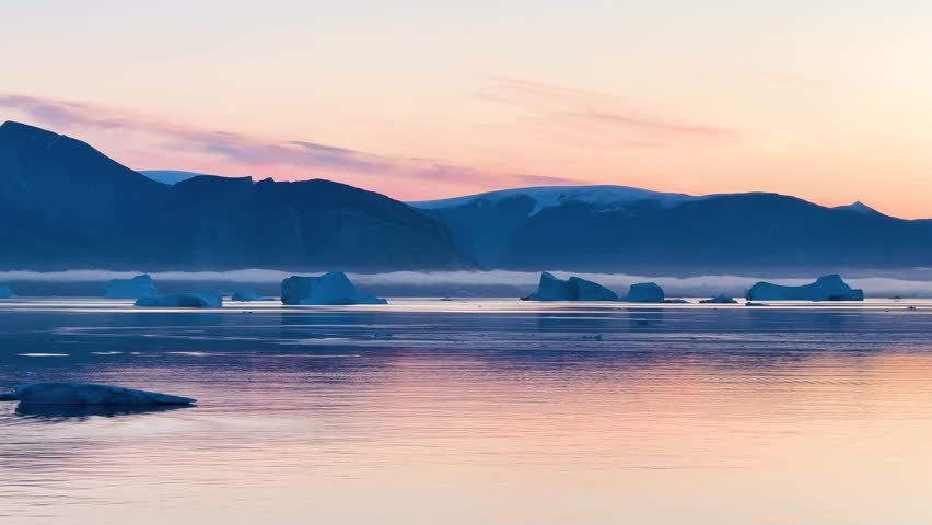 Landscape of Greenland with mountains, icebergs, and calm water in the evening light near the fjord