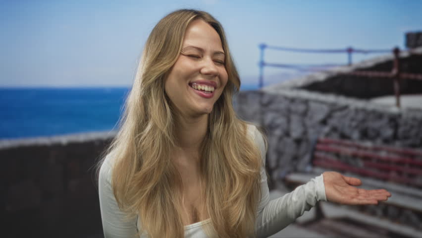 Blonde woman pointing finger to palm on seaside promenade; surprise curiosity.
