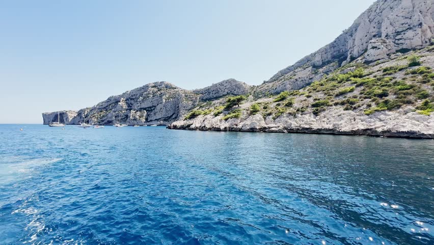Boat ride view of Calanque de Morgiou bay with turquoise Mediterranean water, limestone cliffs and rocky coastline in Calanques National Park on the French Riviera, France.