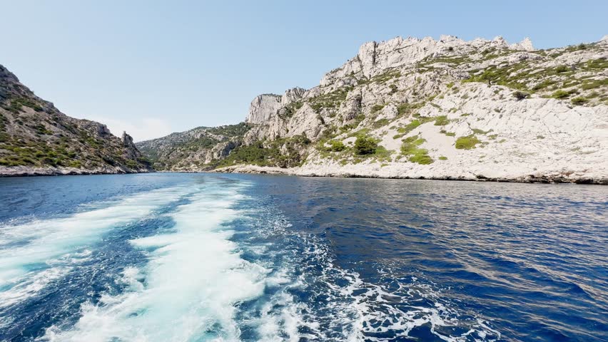 Boat ride view of Calanque de Morgiou bay with turquoise Mediterranean water, limestone cliffs and rocky coastline in Calanques National Park on the French Riviera, France.