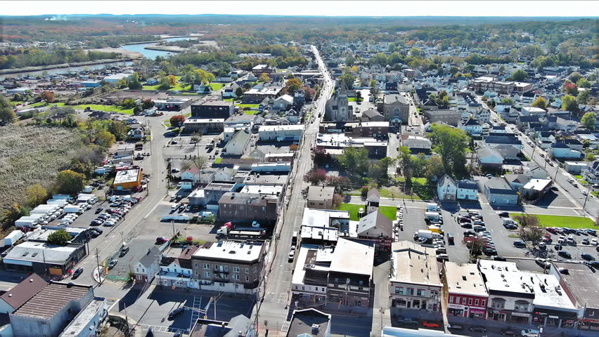 Aerial view American small town Sayreville NJ with vibrant fall colors, busy streets, diverse buildings lined along main road.
