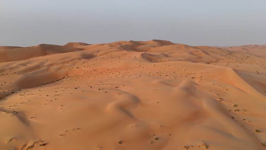 Aerial view of sand dunes in the Empty Quarter desert of the United Arab Emirates during a warm day.