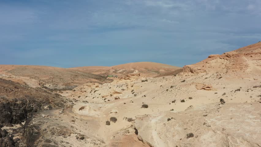 Drone view over the Enchanted Ravine desert in Fuerteventura featuring rugged canyons, dry terrain and scenic geological formations. Perfect stock video for landscapes, travel promotion, outdoor exploration and geographic storytelling.