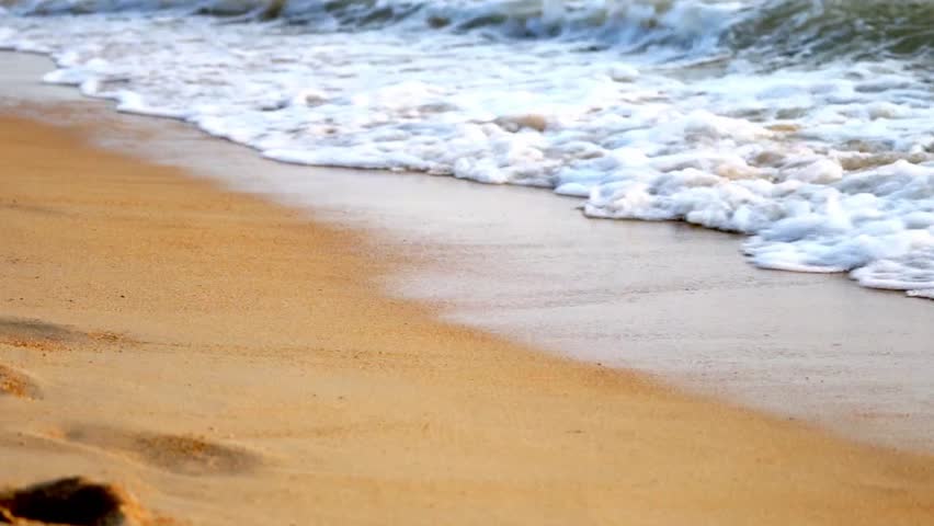 Sea waves on a sandy beach at sunset