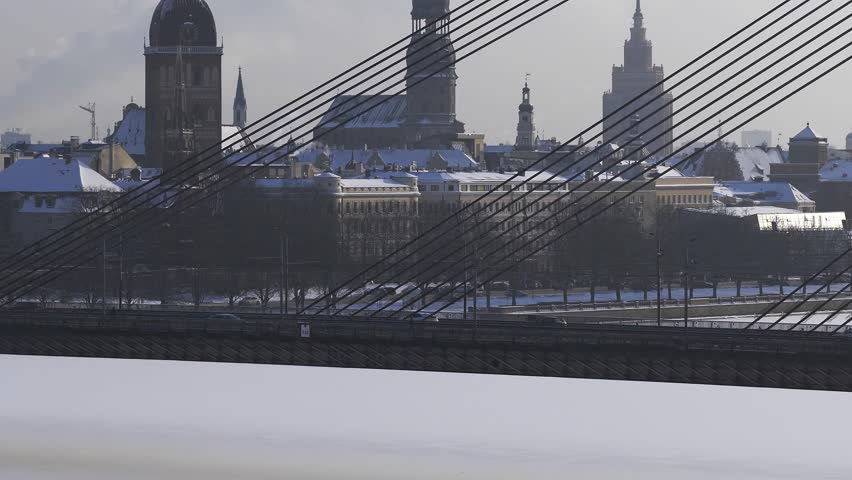 Aerial 4K view of Riga, Latvia, with Vansu Bridge cables, light traffic, frozen Daugava, St. Peter